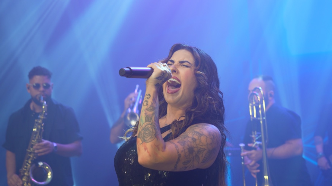 Vocalista da Banda Prime cantando com intensidade sob luz azul
